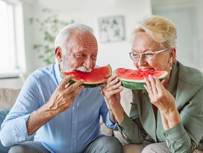 An older couple eat watermelons
