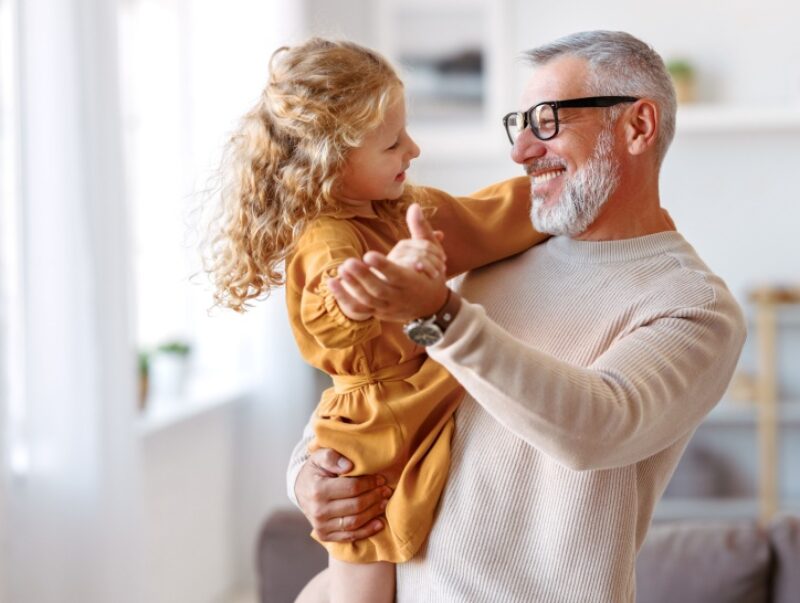 An older man holding his granddaughter