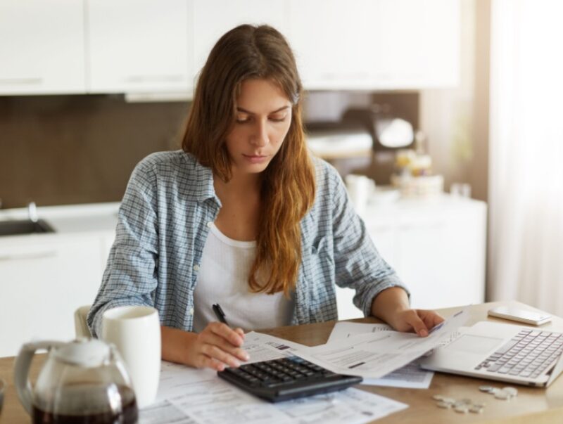 A woman looks at paperwork and uses a calculator