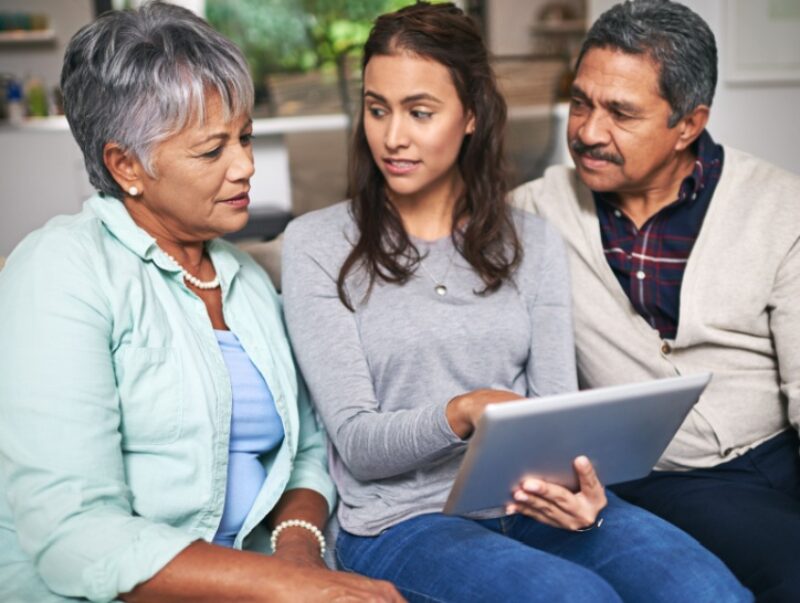 A woman sits with her parents on a sofa