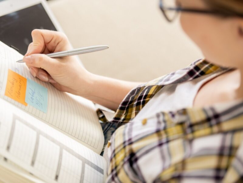 A woman writes notes in a diary