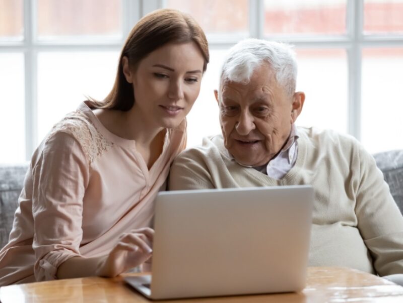 A woman showing an older man how to use a computer
