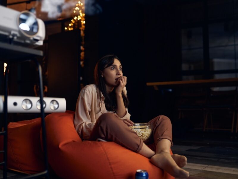 A scared woman watches a film