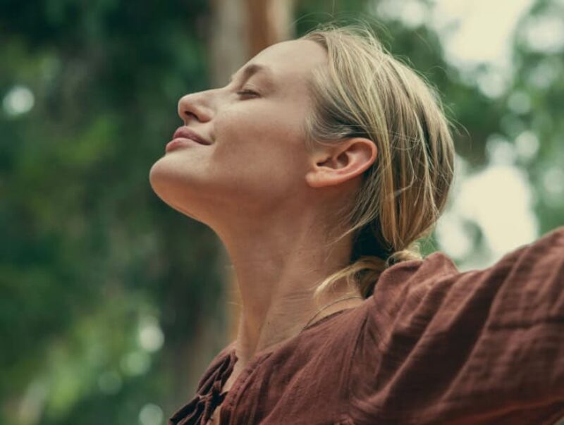 A woman outside in nature taking a deep breath