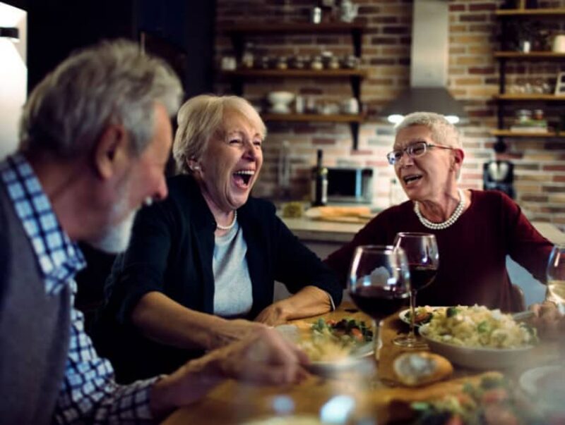 A group of people eating together and laughing