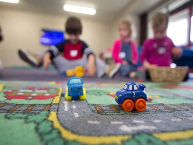 Cars on a playmat with children in the background