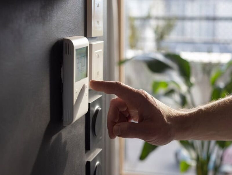 Close-up of a man’s hand adjusting the heating system in his home.