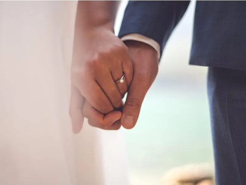 A close-up of a newly married couple holding hands