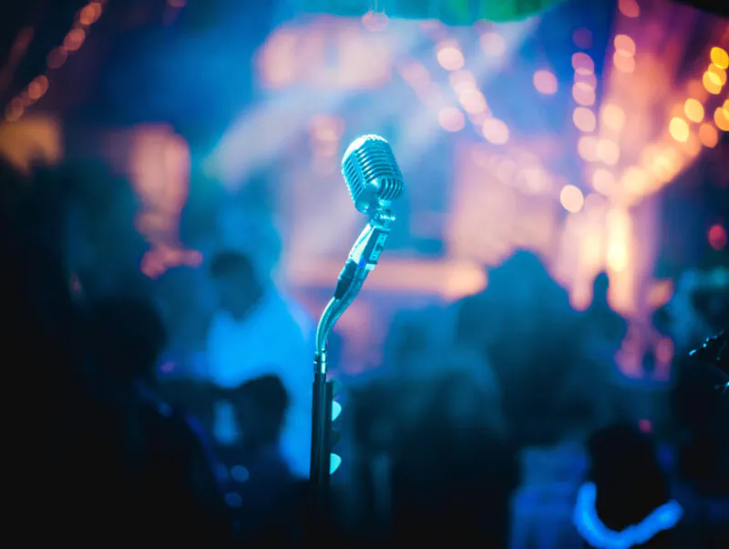 A microphone on a stage with blurred people looking on