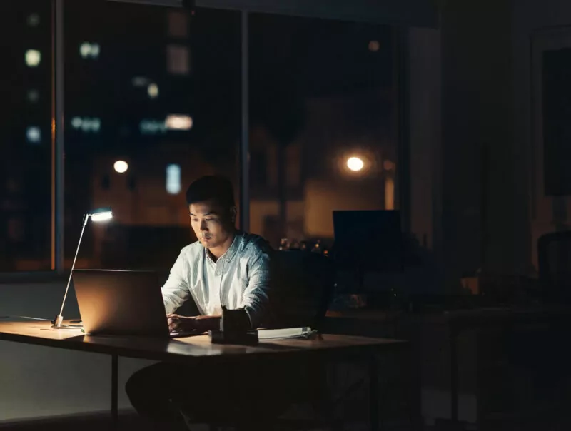 A man works on his laptop in the office at night