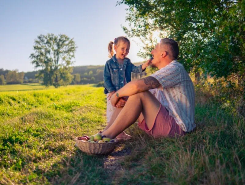 Dad and daughter sitting in the shade during summer