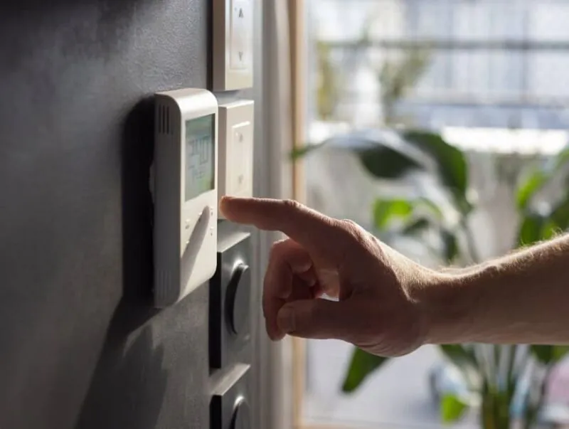 Close-up of a man’s hand adjusting the heating system in his home.